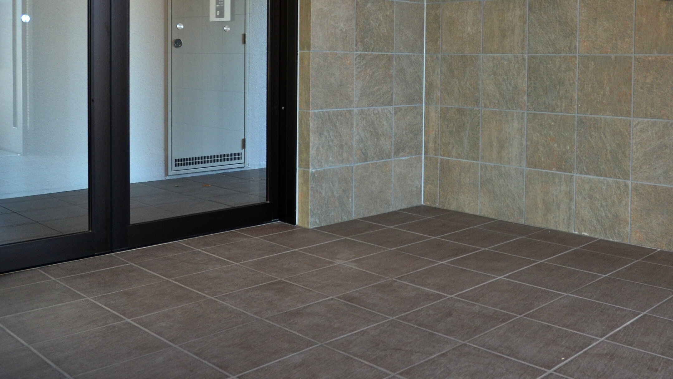 施工例：天然石風の黒300角タイル。使用場所はマンションエントランス