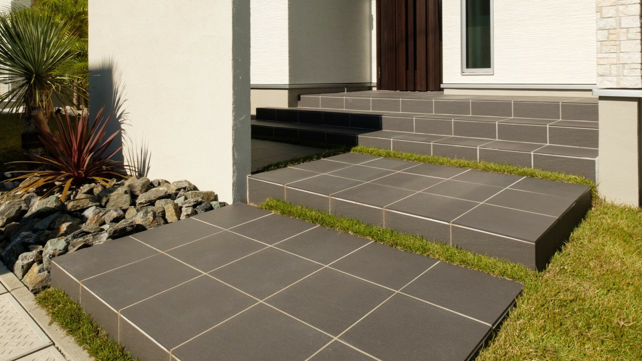 施工例：天然石風の黒300角タイル。使用場所は住宅玄関からアプローチ