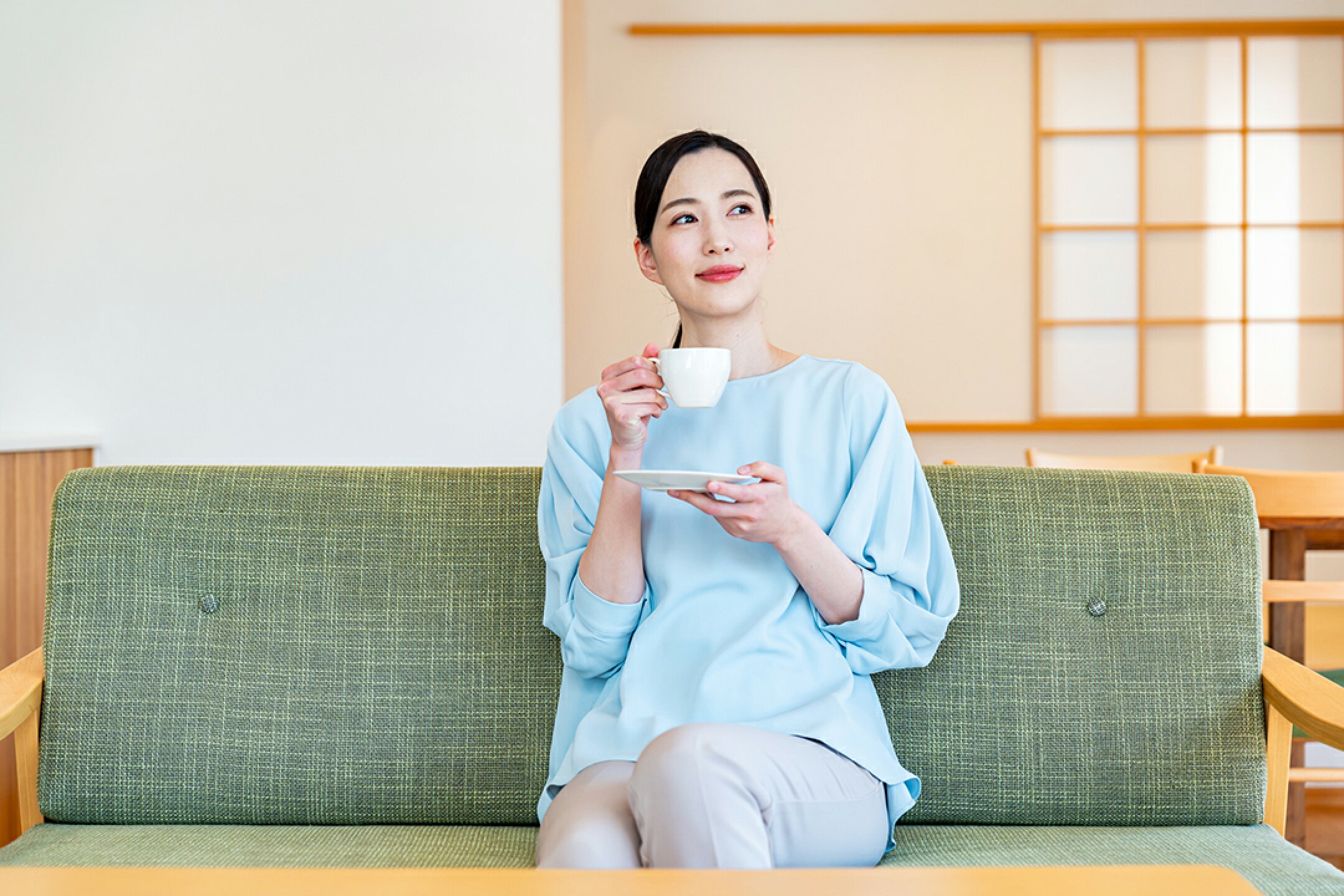 ソファーに座って飲み物を飲む女性