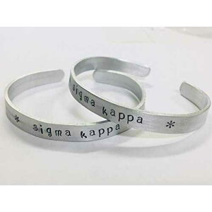 Sigma Kappa �J�t �u���X���b�g - �ϐF���Ȃ��A���~�j�E�����̃J�t�ɕ��ς��ȃt�H���g�Ńn���h�X�^���v����Ă���A�����Ƀ��C�Z���X����Ă��܂��B Ann Peden Jewelry Sigma Kappa Cuff Bracelet - handsta