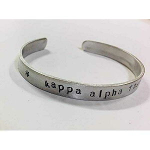 Kappa Alpha Theta �J�t �u���X���b�g - �ϐF���Ȃ��A���~�j�E�����̃J�t�ɕ��ς��ȃt�H���g�Ńn���h�X�^���v����Ă���A�����Ƀ��C�Z���X����Ă��܂��B Ann Peden Jewelry Kappa Alpha Theta Cuff Bracel