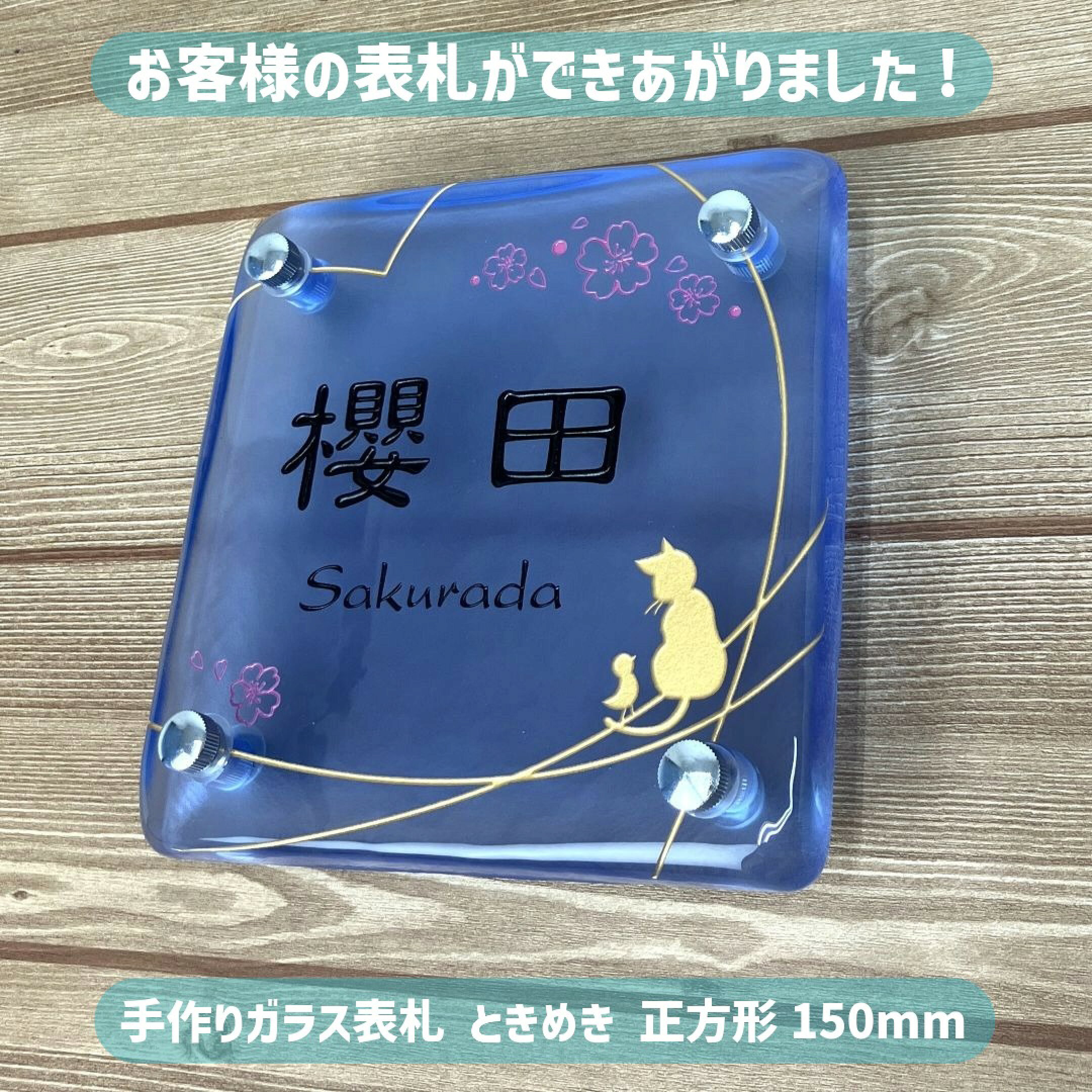 ブルーの手作りガラス表札。文字は黒色。ハート、猫、小鳥のデザインはゴールド、桜のデザインはピンク色。