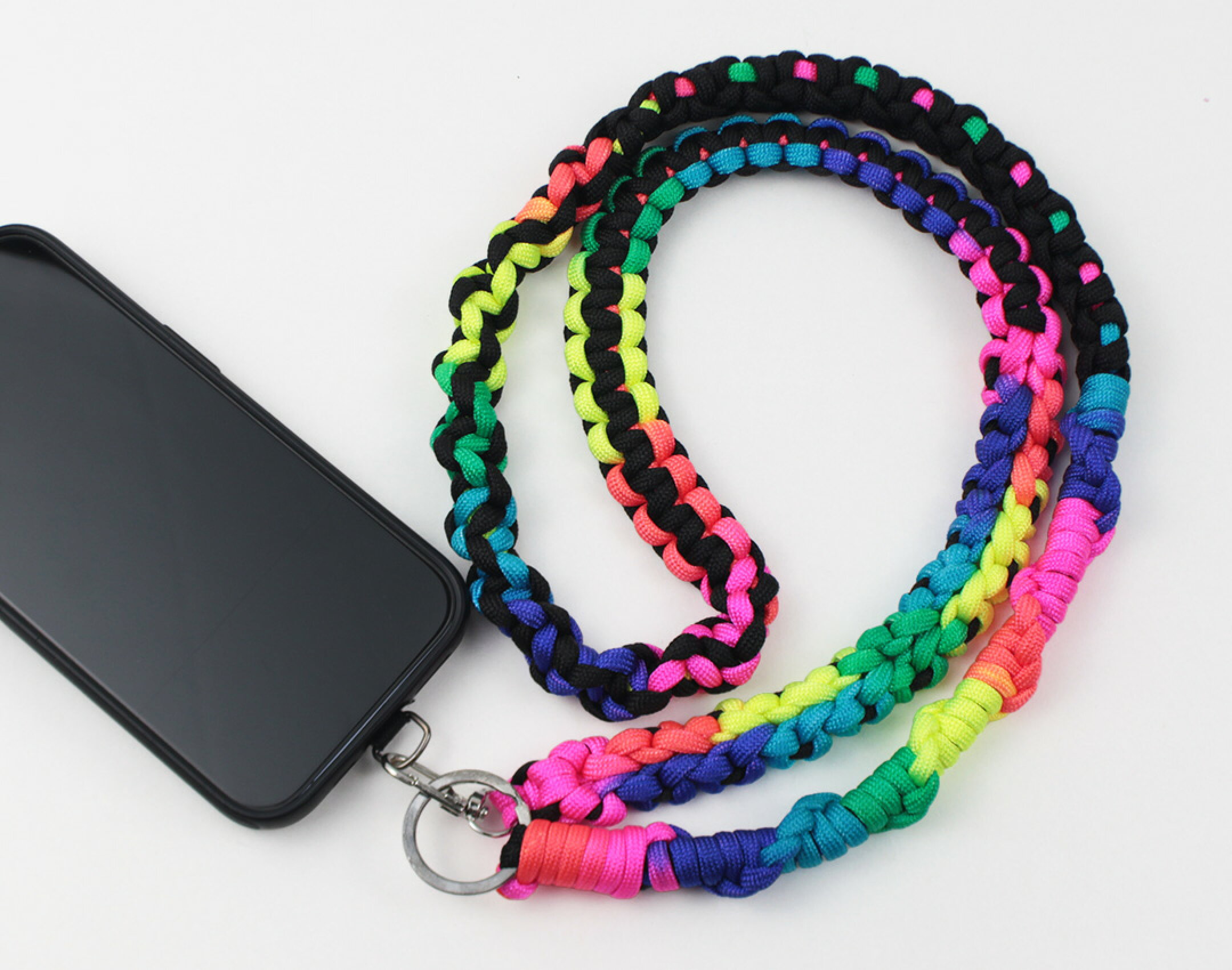 パラコードを使用したハンドメイドスマホショルダーです。レインボーとブラックを組み合わせて明るい発色のある仕上がりにしました。レインボーは１本だけでもカラフルになるのでお勧めのカラーです。