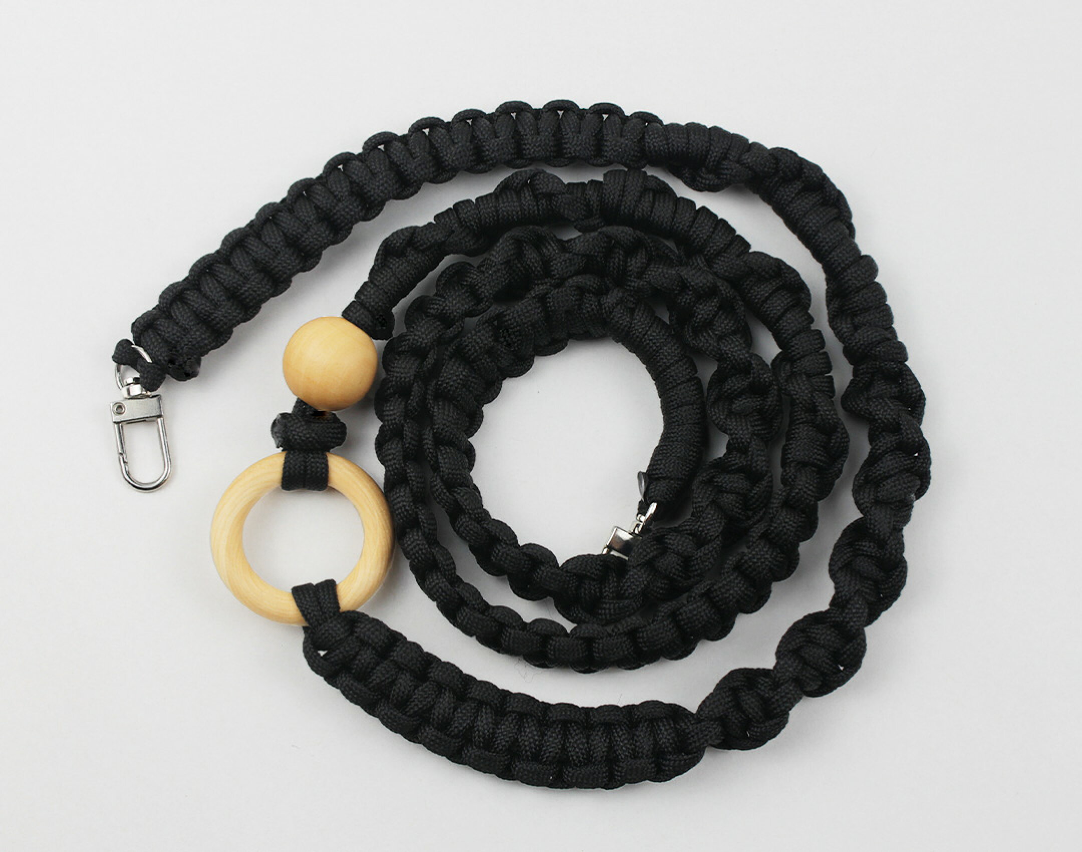 パラコードを使用したハンドメイドスマホショルダーです。木製のリングとビーズをアクセントにして個性的な作品に。パラコードはブラックのみを使用しましたが、パーツを組み合わせることで印象がとても変わります。