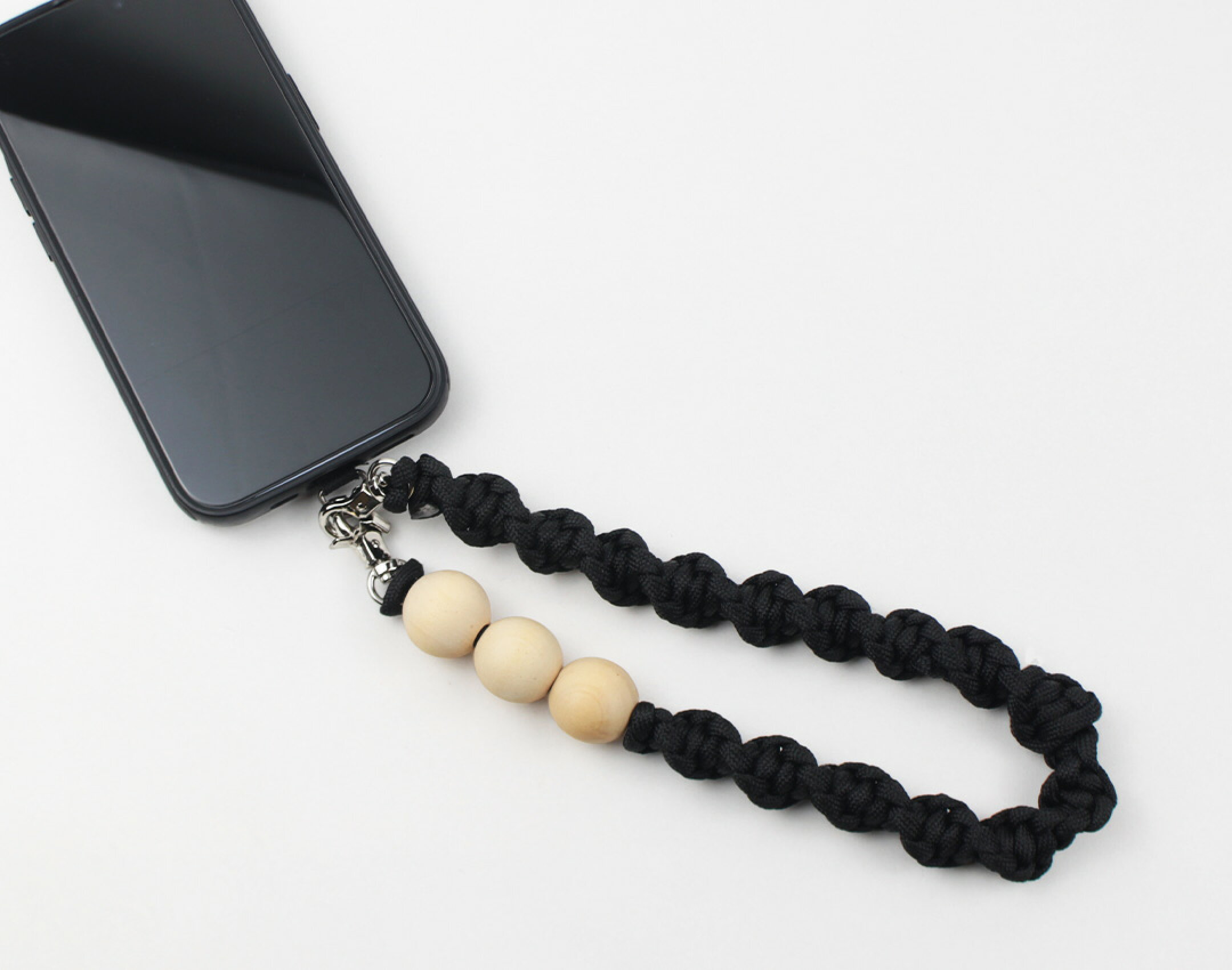 パラコードを使用したハンドメイドスマホストラップです。ウッドビーズを使用したシンプルな作品です。編み方も同じにして強弱の出ないデザインに。３連木製ビーズが可愛い。バッグやポケットからチラッと見せるのもいいですね。