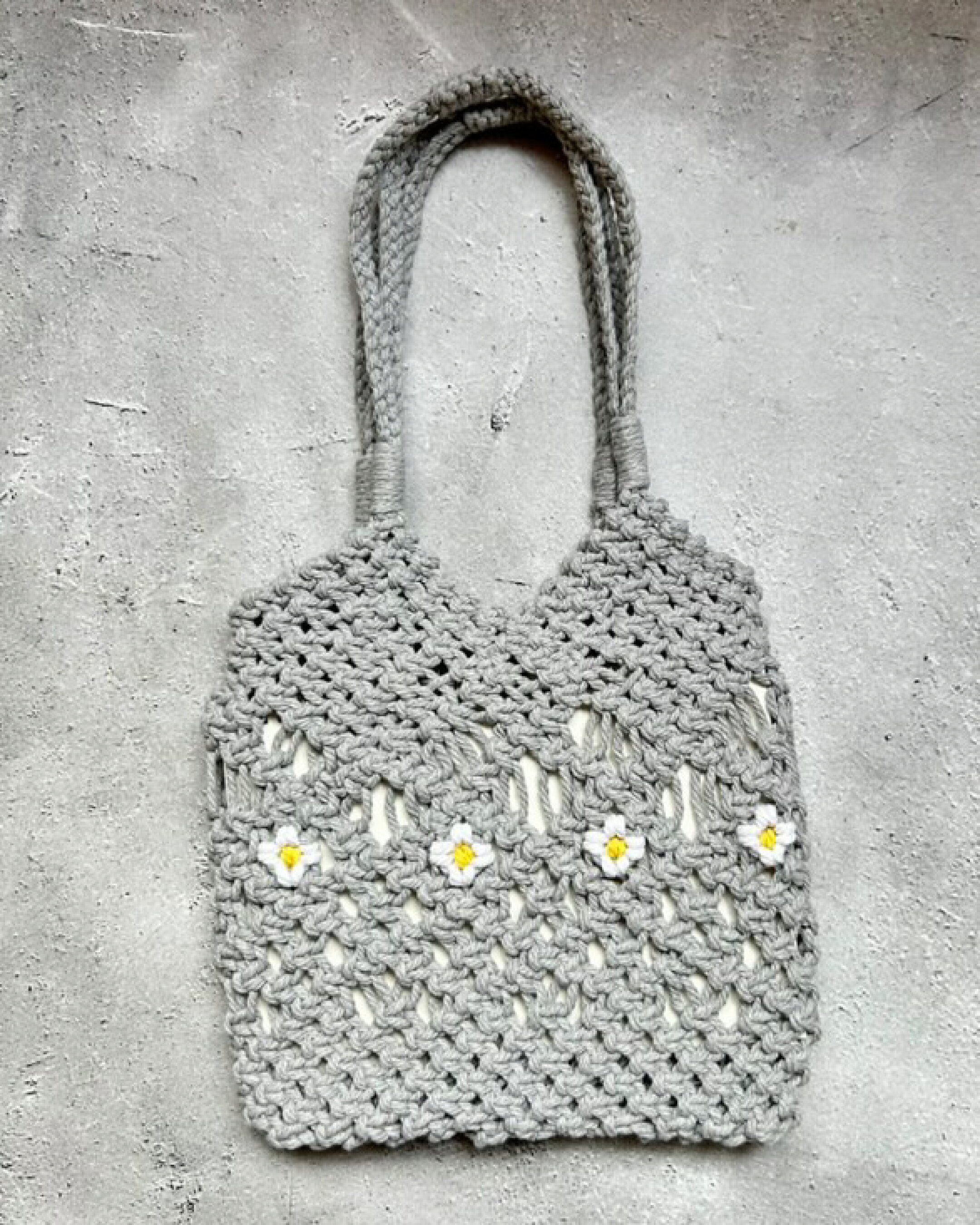 マクラメーロープを使用したトートバッグです。ホワイトのお花をポイントにしたかわいらしいデザインです。ちょっとしたお出かけにぴったりサイズです。柔らかくて編みやすいので大きな作品作りにも使いやすいマクラメ糸になります。