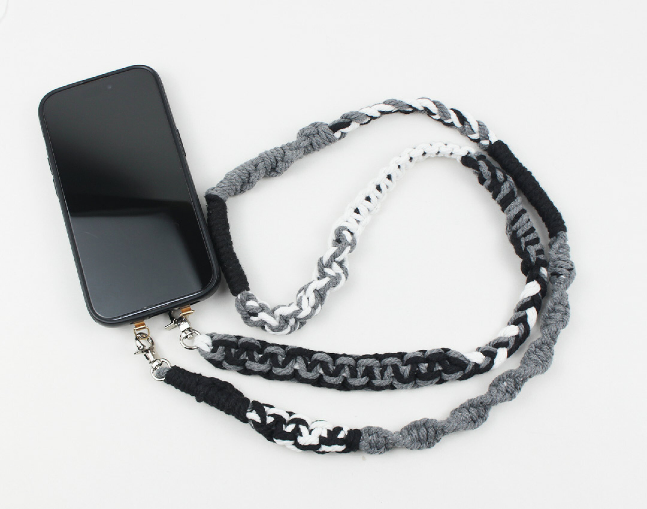マクラメ糸を使用したスマホショルダーです。ブラック、ホワイト、グレーを使用したどなたでも使いやすいカラーになります。平編みなどの編み方をいくつも作ることで個性的なデザインになるように仕上げました。コットンならではの優しさを生かしています。