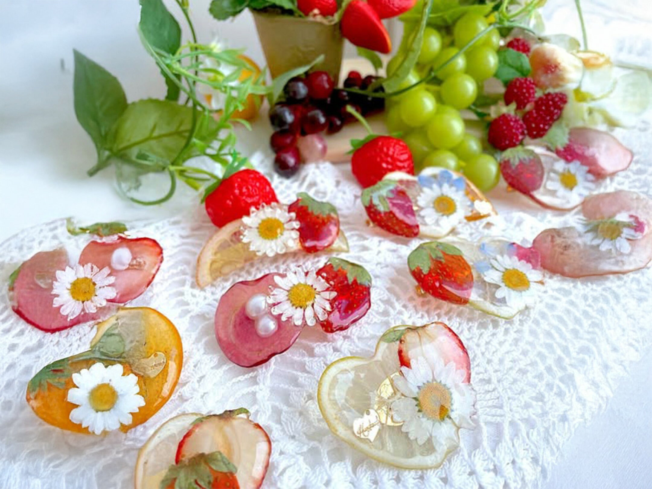 小さないちごと可憐な花を透明感あふれるレジンに閉じ込めた春らしいハンドメイドアクセサリー。ころんとしたお菓子のようなフォルムと大ぶりいちごが陽ざしにきらめく華やかなデザイン