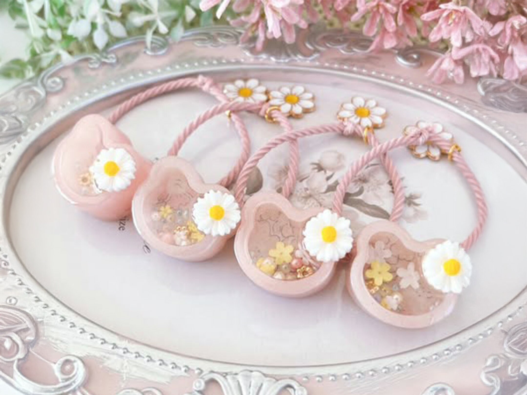 淡いピンクにラメがきらめく、クマ型のレジンシェイカーアクセサリー。小さなお花やハートを閉じ込めた透明感のあるデザインが、春のやさしい空気を感じさせます。見て癒され、手に取るとほっと心がゆるむ、ときめきを詰め込んだ作品です。