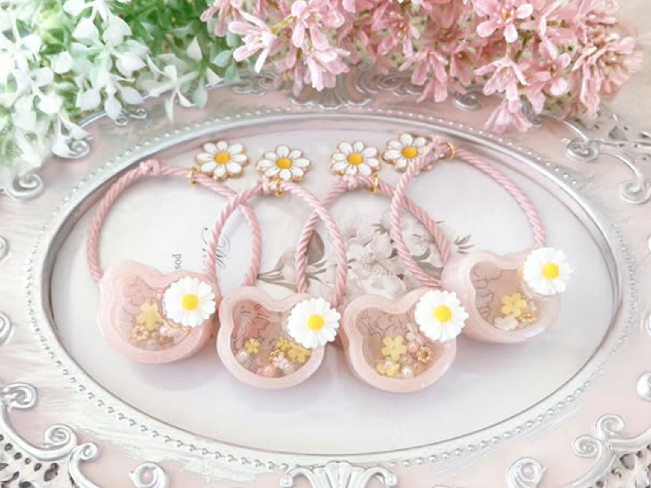 淡いピンクのクマ型シェイカーに小さな花やラメを閉じ込めた、ハンドメイドレジンのヘアアクセサリー。春らしいやさしい色合いと透明感が可愛らしく、並べて飾っても癒されるデザイン