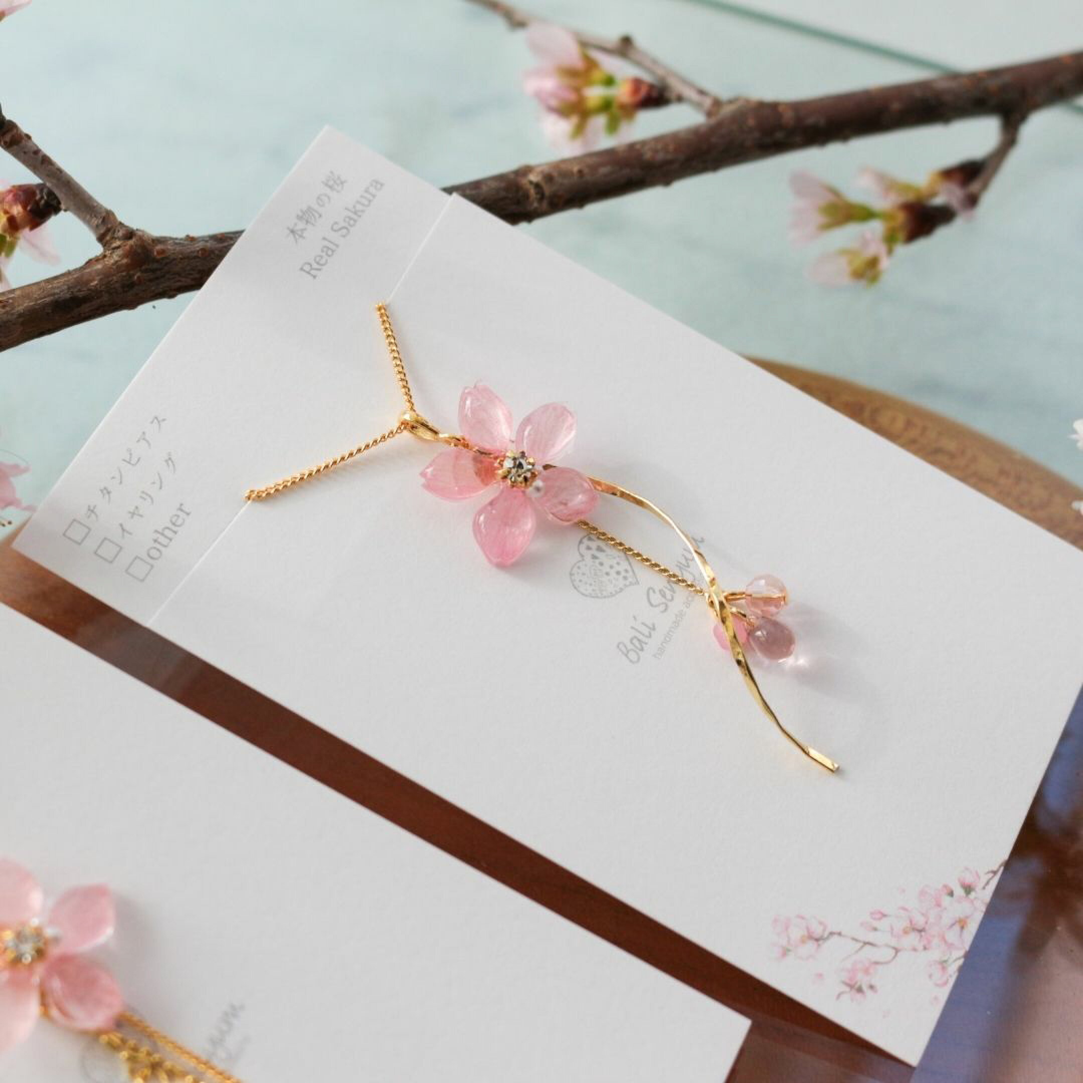 本物の桜アクセサリー。ブランドBali Senyum（バリセニュン）の本物のソメイヨシノを使用したネックレス。入学式や卒業式などのハレの日のコーディネートにおすすめです。シーンに合わせて選べる長さで、相手の好きなタイプや長さをギフトにしても喜ばれます。