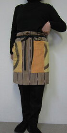 個性派エプロン・ワイドは動き易くて尻隠す・こちらはオレンジと黄色の無地と茶系の絣生地がコンビ